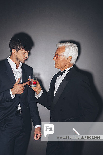 Junger Mann im Gespräch mit einem eleganten älteren Mann mit einem Drink