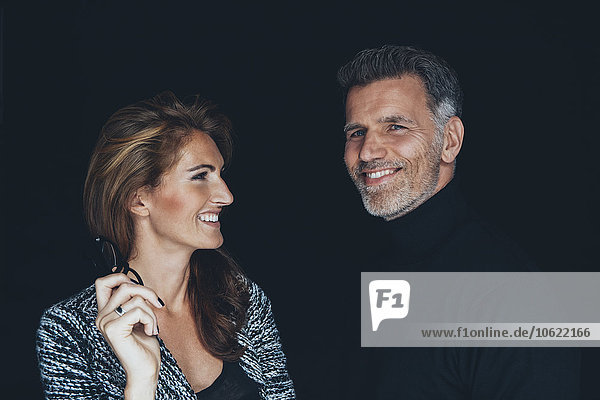 Portrait of smiling couple in front of black background