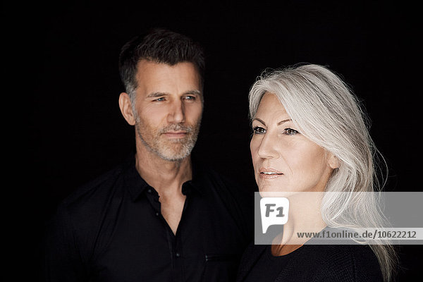Portrait of mature man and mature woman wearing black clothes in front of black background
