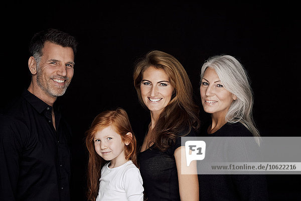 Porträt von drei Generationen Familie vor schwarzem Hintergrund