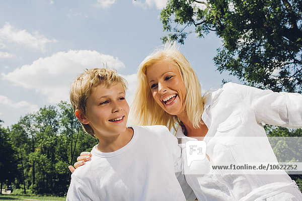 Porträt einer glücklichen Mutter und ihres Sohnes  die zusammen in einem Park spielen.