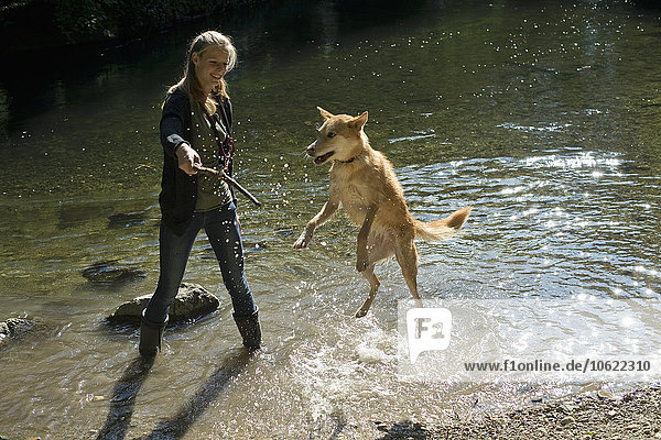 Junge Frau spielt mit ihrem Hund in der Natur