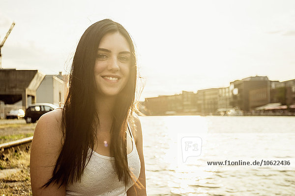 Deutschland  Münster  Porträt einer lächelnden jungen Frau vor dem Stadthafen