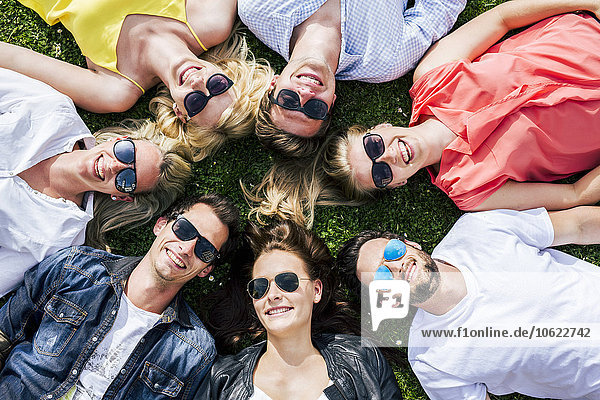 Happy friends wearing sunglasses lying in meadow together