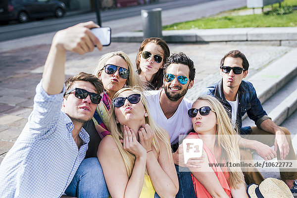 Glückliche Freunde  die eine Sonnenbrille tragen und einen Selfie nach draußen bringen.