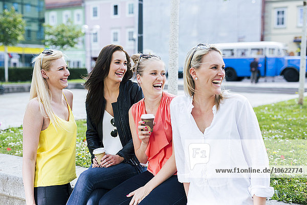 Vier junge Frauen  die draußen lachen und sich umdrehen.