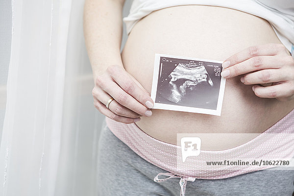 Schwangere Frau mit Ultraschallbild vor dem Bauch
