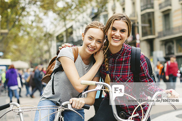 Spain  Barcelona  two young women on bicycles in the city