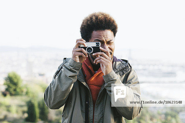 Porträt eines jungen Mannes  der mit einer alten Kamera fotografiert.