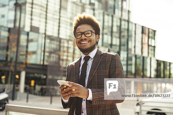 Smiling young businessman outdoors with cell phone