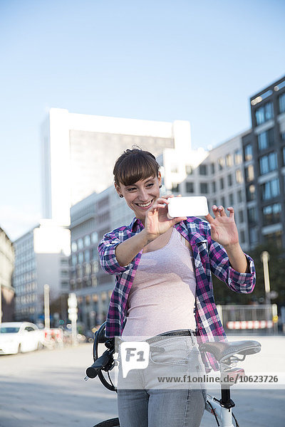 Deutschland  Berlin  junge Frau beim Fotografieren mit ihrem Smartphone