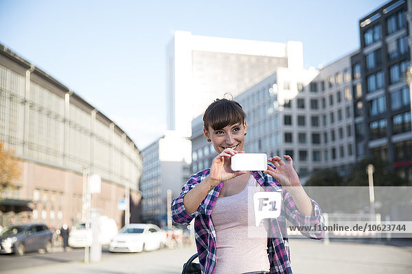 Deutschland  Berlin  junge Frau beim Fotografieren mit dem Smartphone