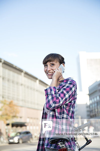 Germany  Berlin  portrait of young woman telephoning with smartphone