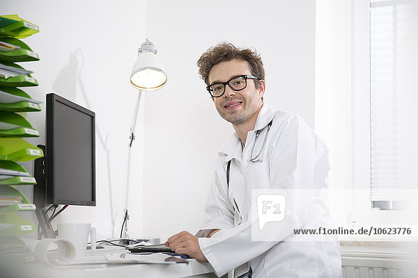 Portrait of smiling doctor sitting at desk