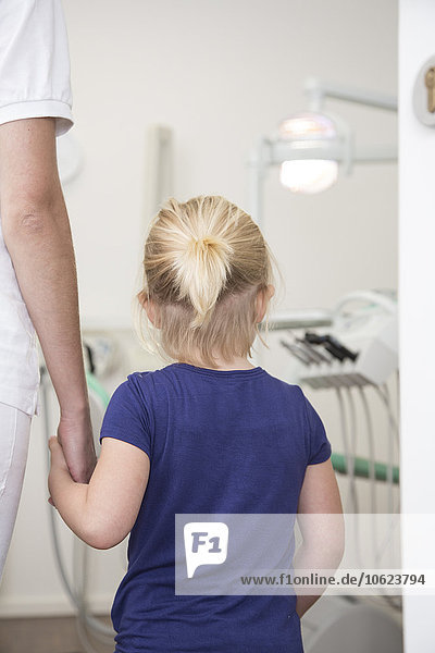 Zahnarzthelferin hält Mädchenhand vor der Behandlung