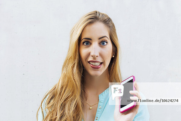 Portrait einer jungen blonden Frau mit Smartphone