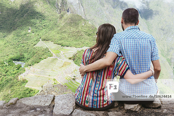 Peru  Paar sitzend und mit Blick auf die Zitadelle Machu Picchu