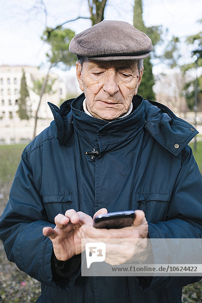 Porträt eines älteren Mannes mit Smartphone im Park