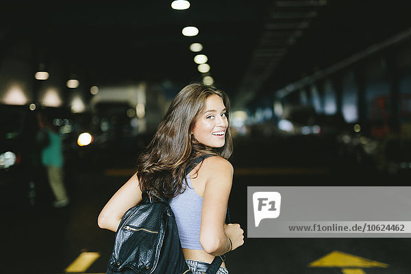 Smiling woman with a backpack ready to enter into a parking lot