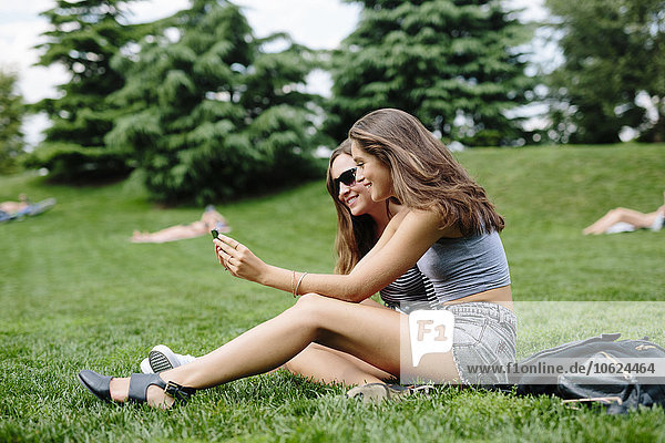 Two happy friends in a park looking at cell phone