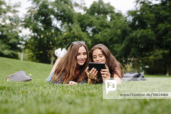 Two friends in a park looking at cell phone