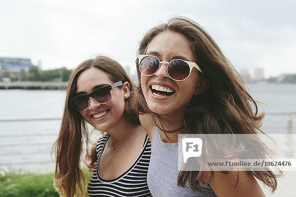 USA  New York City  two happy friends wearing sunglasses at Hudson River