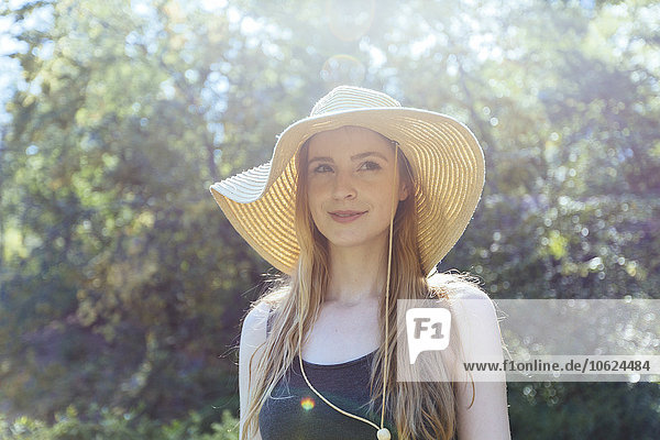 Porträt einer lächelnden jungen Frau mit Sommerhut