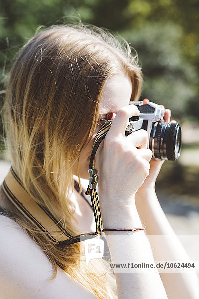Blonde junge Frau beim Fotografieren im Freien