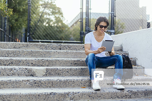 Man sitting on steps using digital tablet