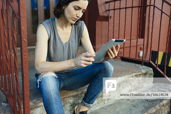 USA  New York City  Frau auf der Treppe sitzend mit digitalem Tablett
