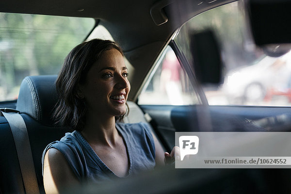 Portrait of happy young woman sitting inside of a cab