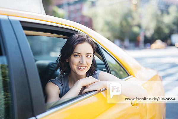 USA  New York City  portrait of smiling young woman sitting inside of yellow cab