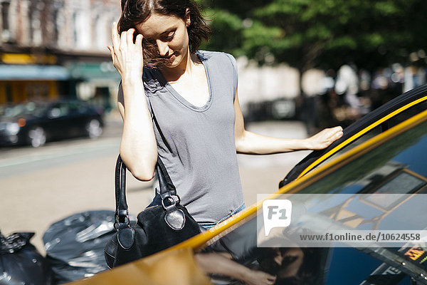 USA  New York City  junge Frau beim Einsteigen in ein gelbes Taxi