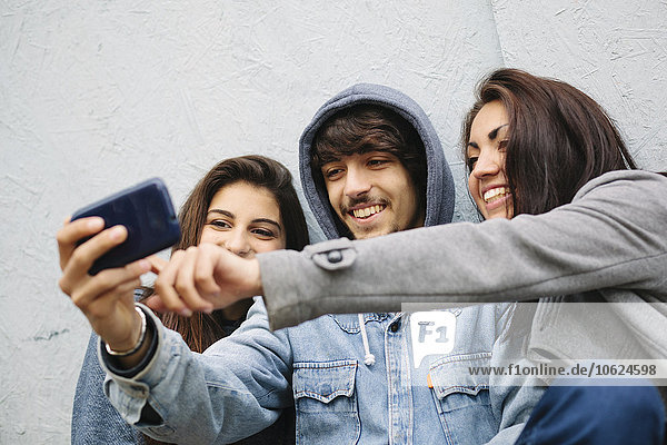 Three friends taking a selfie with cell phone