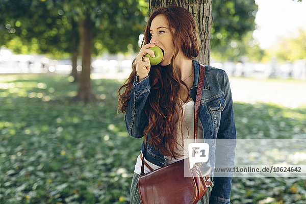 Frau isst einen Apfel im Park