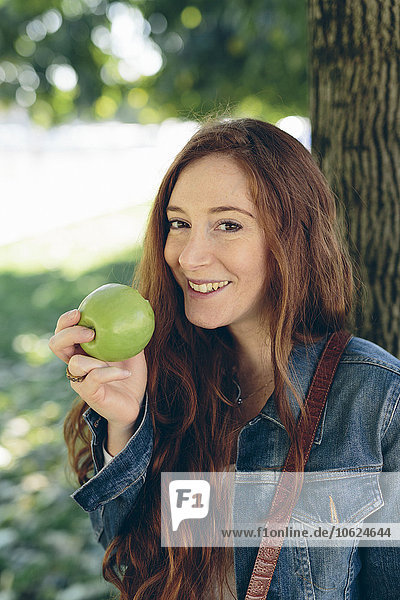 Lächelnde Frau mit einem Apfel im Park