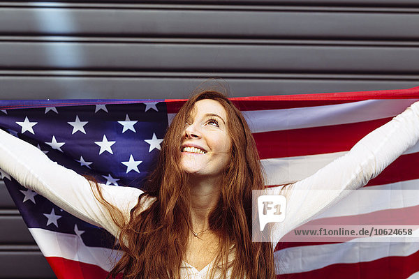 Lächelnde Frau hält eine amerikanische Flagge mit Zuversicht