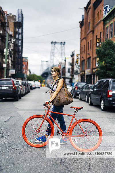USA  New York City  Williamsburg  woman withg red racing cycle crossing the street