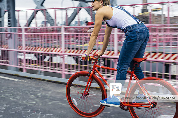 USA  New York City  Williamsburg  Frau mit rotem Rennrad auf der Williamsburg Bridge