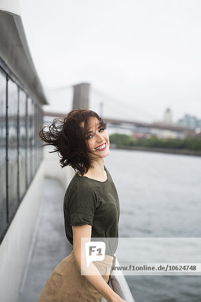 USA  New York City  Portrait einer jungen Frau  die an einem windigen Tag auf einem Ausflugsboot steht.