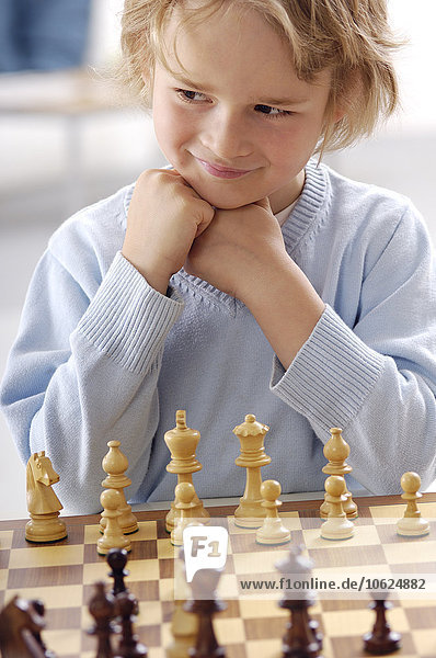 Porträt eines lächelnden kleinen Jungen beim Schachspiel
