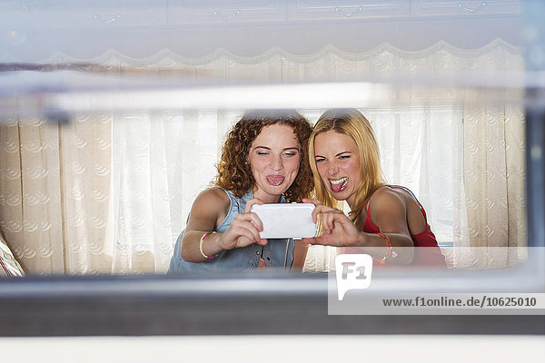 Zwei Freundinnen  die einen Selfie in einem Wohnwagen mitnehmen.
