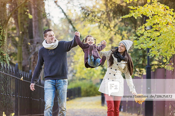 Parents lifting up daughter in autumnal park