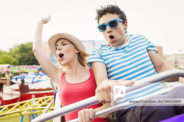 Happy couple at fun fair riding roller coaster
