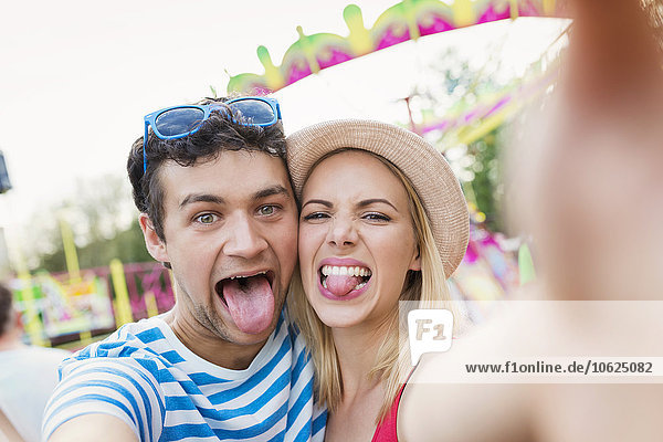 Ein glückliches Paar auf dem Jahrmarkt  das sich selbst mit Zungen herausnimmt.