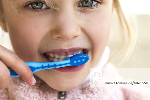 Little girl brushing her milk teeth  close-up