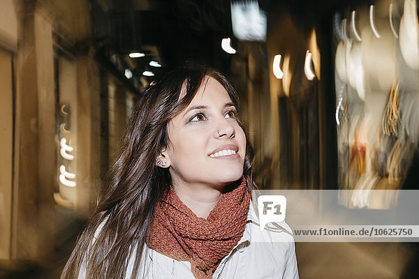 Spanien  Reus  Porträt einer lächelnden jungen Frau  die nachts durch die Stadt läuft.