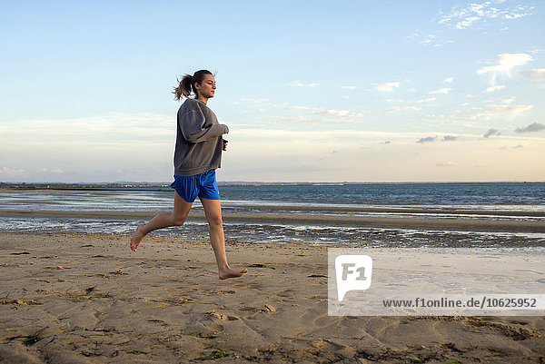 Spain  Puerto Real  young woman jogging on the beach at evening twilight