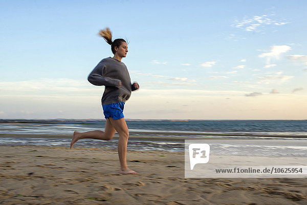 Spain  Puerto Real  woman jogging on the beach at evening twilight