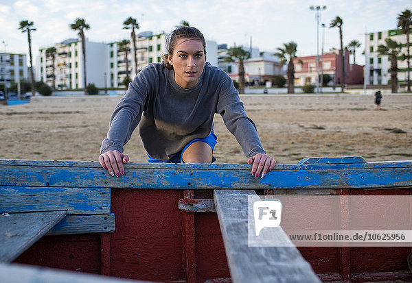 Spanien  Puerto Real  Porträt einer jungen Frau beim Stretching am Strand